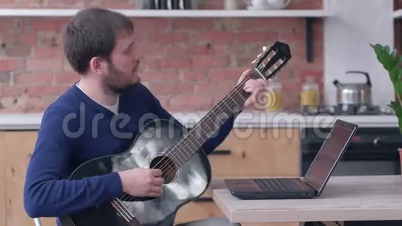 梅里胡子吉他手男性学习演奏弦乐器使用笔记本电脑在线视频教学视频的预览图