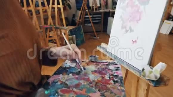 有才华的艺术学生在调色板上混合颜色然后在画布上画花而她的专业老师则是视频的预览图