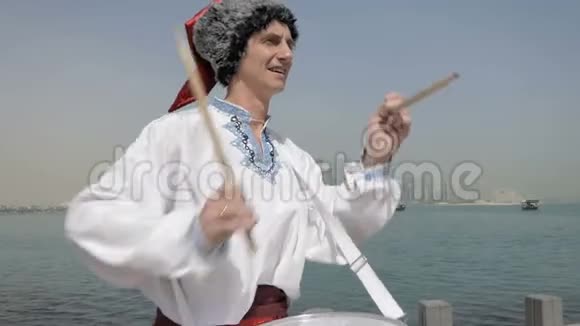 快乐的人穿着邋遢的西装高跷在海上码头打鼓视频的预览图