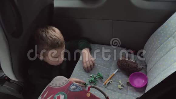 一个男孩坐在汽车地板上在后座上玩一些玩具视频的预览图
