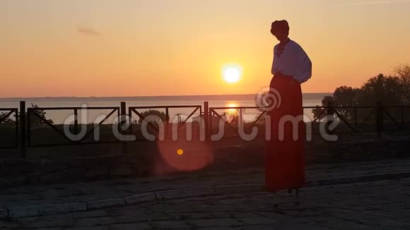 穿着乌克兰西装的男人在夕阳西下的海边踩着高跷跳舞视频的预览图