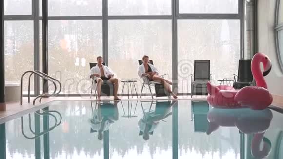 男孩和女孩坐在游泳池附近水上有粉红色的火烈鸟视频的预览图