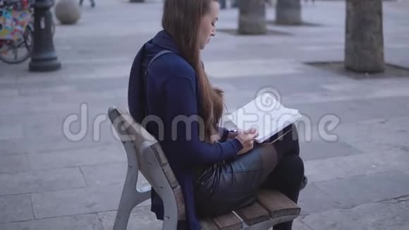 坐在城镇广场上的妇女在她的素描书上画素描视频的预览图
