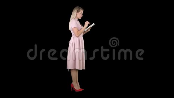 使用平板电脑观看粉色服装侧视的年轻女性阿尔法频道视频的预览图