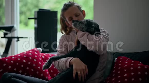 沙发上的年轻女子和她的狗抱在一起视频的预览图
