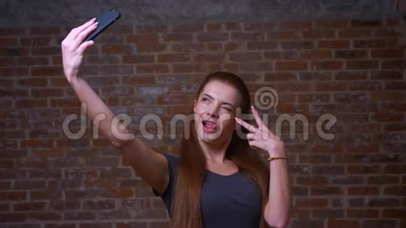 惊人的白人姜女在智能手机的网络摄像头上拍摄自拍照片展示自己的幸福视频的预览图