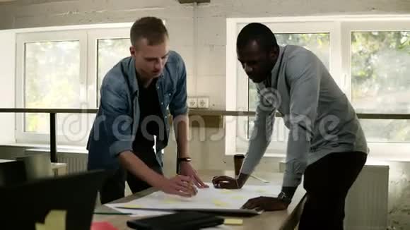 两个商业伙伴正在一起工作集思广益指着桌子上写着视频的预览图