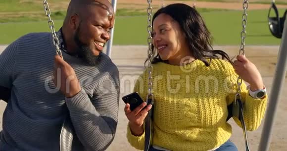在阳光明媚的4k天快乐的一对夫妇在公园里使用手机视频的预览图