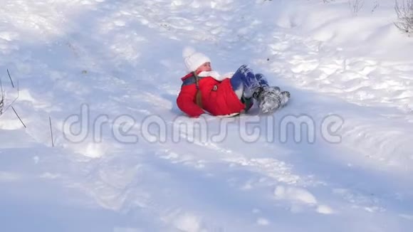 在冬天的公园里快乐的女孩骑着雪橇在雪山上圣诞节周末孩子们在公园里玩耍视频的预览图