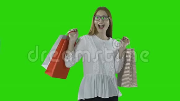 快乐女孩带着纸袋在一个孤立的绿色背景下的购物中心购物后视频的预览图