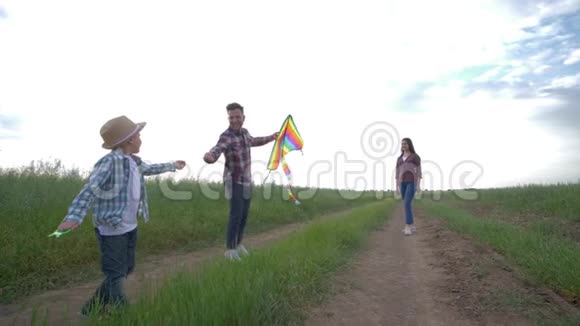 一家人放风筝儿子和爸爸妈妈在天空的背景下在大自然的休息中在乡间奔跑视频的预览图