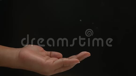 在黑色背景下将白色婴儿滑石粉倒入女性手中视频的预览图