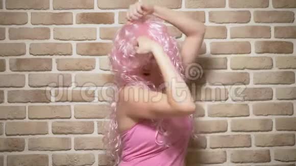 有着粉红色卷发的疯狂女孩用二头肌抵住砖墙复制空间幽默的概念冒险视频的预览图