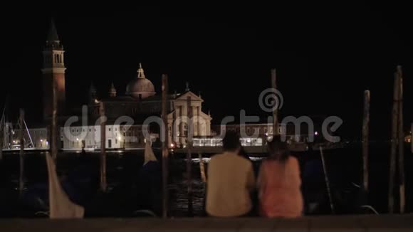 一对夫妇坐在河堤前的威尼斯夜景视频的预览图