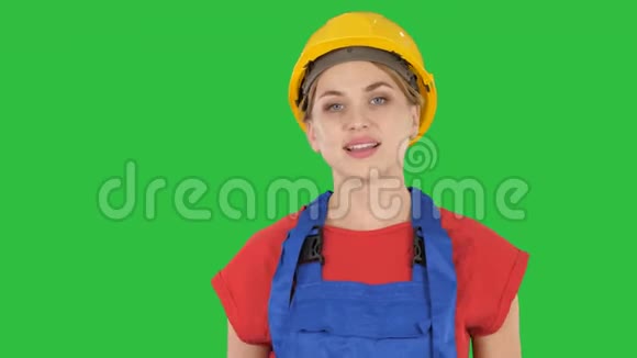 微笑的建筑工人妇女站着变换姿势双手折叠双手放在臀部双手放在绿色的口袋里视频的预览图