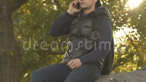 男人用手机说话坐在大石头上手机连接不良视频的预览图