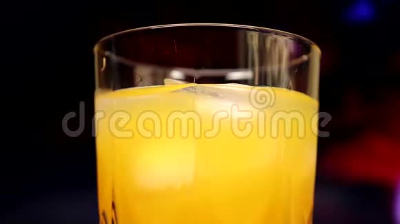 用黄色橙色甜多果汁和冰块慢慢旋转的玻璃视频的预览图