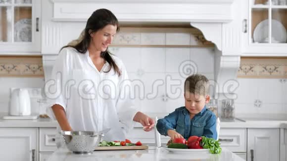中弹小男孩在家厨房用刀子和木板做沙拉时帮助他的母亲视频的预览图