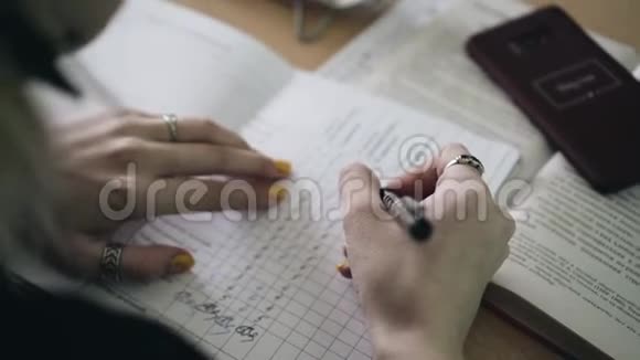 女孩在笔记本上填写数字表从她肩膀上看到的快关门视频的预览图