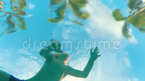 从棕榈树的游泳池底部看风景还有一个小孩在镜头前游泳视频的预览图