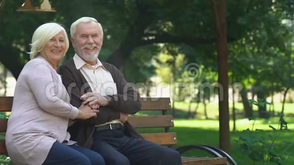 老夫妇坐在长凳上高兴地看着他们的孙子们玩得很开心视频的预览图