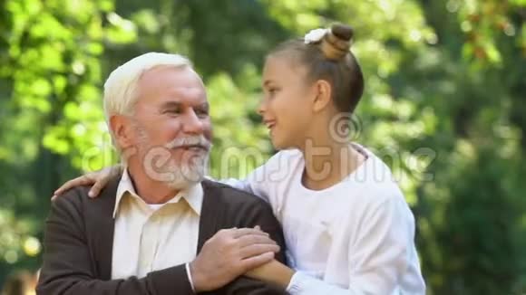 可爱的小女孩微笑着拥抱她的祖父闲暇时间和家人在一起视频的预览图
