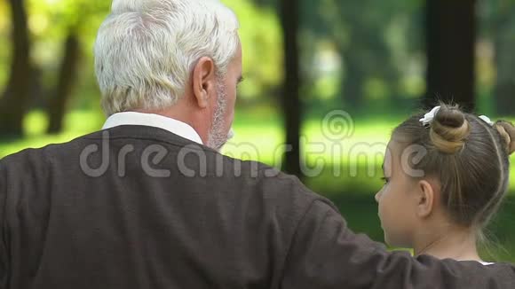 祖父讲故事坐在公园的长凳上带着孙子孙女视频的预览图