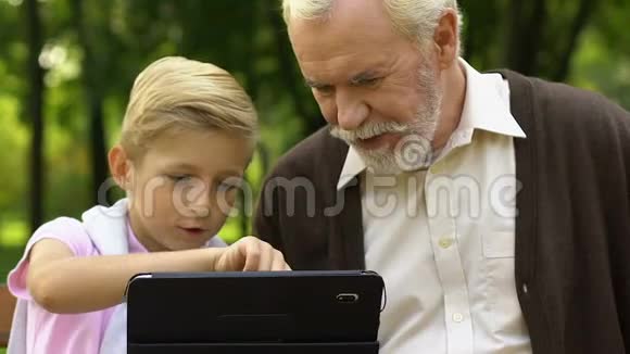 孙子在平板电脑上展示老爷爷的游戏新的现代数字技术视频的预览图