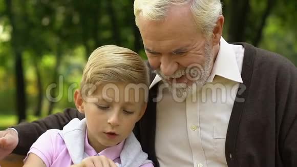 小男孩教他的祖父用智能手机打电话技术视频的预览图
