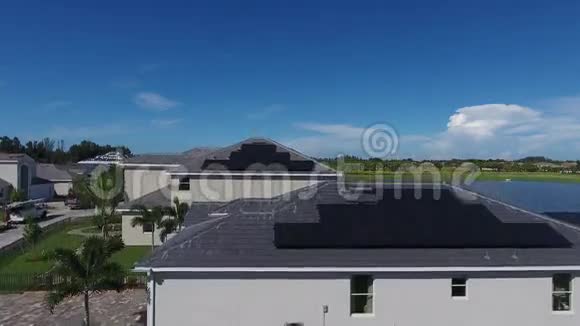 屋顶上有生态太阳能电池板的4k空中拍摄带湖的小郊区景观视频的预览图