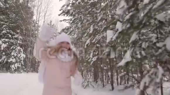 一个快乐的少年女孩在雪地公园跑步而冬天走慢动作视频的预览图