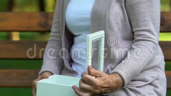 老太太坐在长凳上打开盒子戴着古董戒指悲伤的回忆视频的预览图