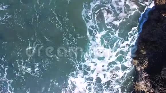 从海滩悬崖上走到起伏的大海在印度尼西亚巴厘岛的海岸上环境可持续性概念视频的预览图