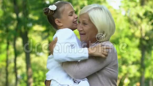 小可爱的女孩紧紧地拥抱她的祖母在白天公园家庭周末视频的预览图