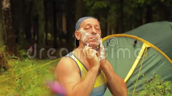 一个人坐在旅游帐篷附近刮脸视频的预览图