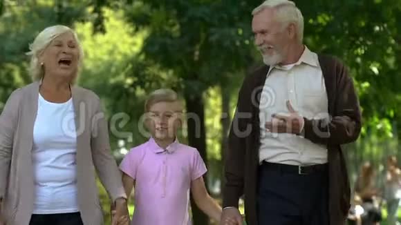 小男孩和爷爷奶奶一起在公园散步一起享受快乐时光视频的预览图