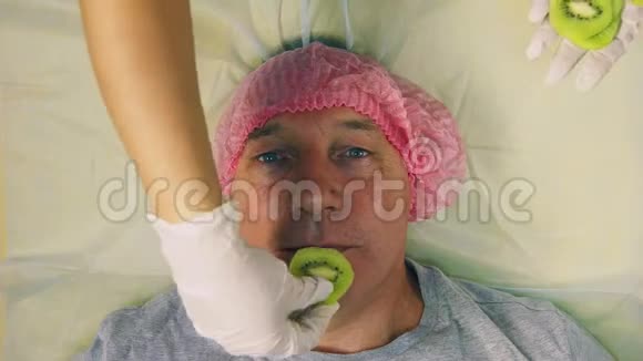 美容师女人的手放在男人的脸上一圈水果猕猴桃作为面部的水果面具视频的预览图