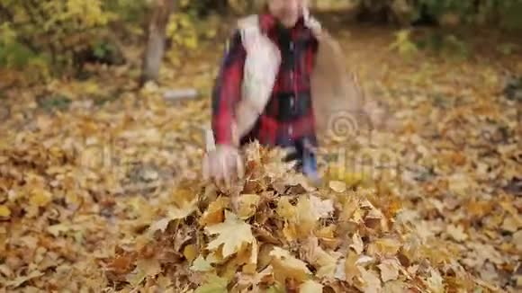快乐的女孩加速跳进一大堆树叶里大笑起来视频的预览图