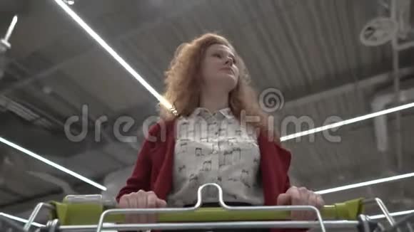 年轻漂亮的女人穿过超市购物车视图视频的预览图