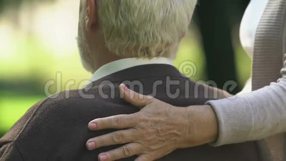 老妇人小心翼翼地抱着丈夫坐在长凳上关系信任视频的预览图