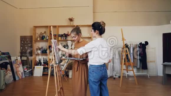 开朗的女士和她的女教师一起用画笔和油画画视频的预览图