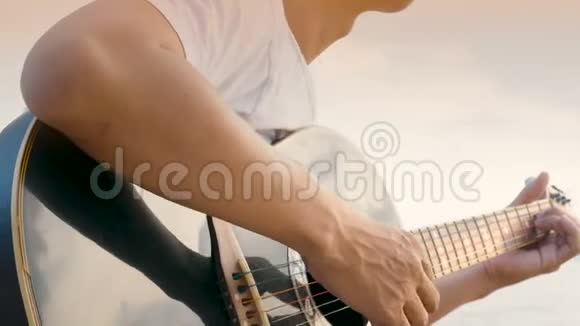 4K接近一个男人在日落时在海滩上弹声吉他感觉放松视频的预览图