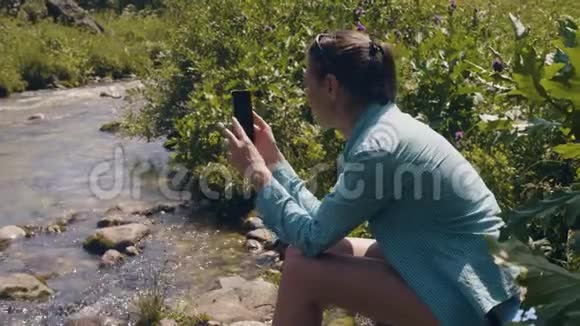 女游客在河边休息用手机拍照视频的预览图
