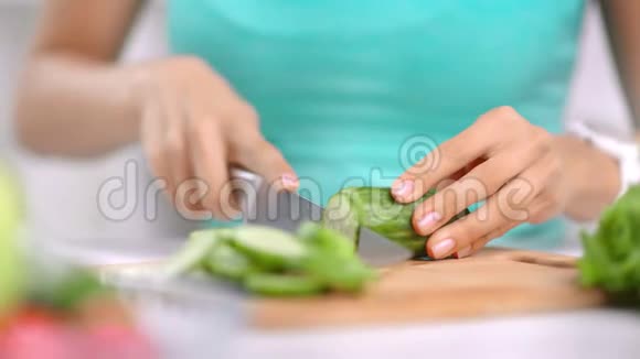 特写女性手切新鲜有机黄瓜用刀烹饪健康食品视频的预览图