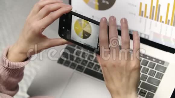女性手拿手提电脑屏幕上统计数据的移动照片视频的预览图