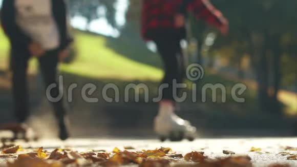 滑板运动员在公园的落叶上骑滑板关注前景慢动作视频的预览图