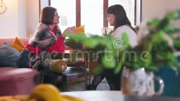 两个年轻的女人坐在咖啡馆里边喝咖啡边说话上景视频的预览图
