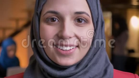 年轻漂亮的阿拉伯女性脸上戴着灰色头巾直视着镜头有着漂亮的棕色眼睛视频的预览图