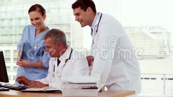 微笑的医生在他的电脑上向他的同事展示一些东西视频的预览图