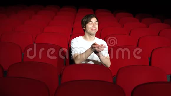 一个人独自坐在空荡荡的电影院或剧院里鼓掌视频的预览图